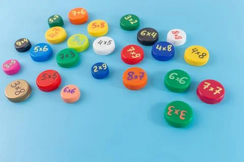 Colorful bottle caps with multiplication problems arranged on a blue backgr.. Stock Photos