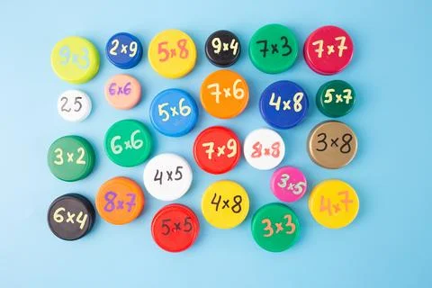 Colorful bottle caps with multiplication problems arranged on a blue backgr.. 스톡 사진
