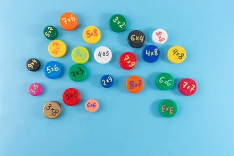Colorful bottle caps with multiplication problems on a blue background. Fla.. Stock Photos