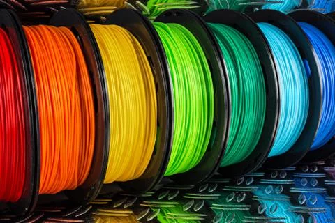 Colorful bright  row of spool 3d printer filament black metal background Stock Photos