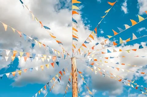 Colorful bright triangular Bunting flags on a blue sky background with white 写真素材