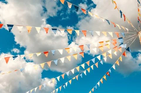 Colorful bright triangular Bunting flags on a blue sky background with white 写真素材