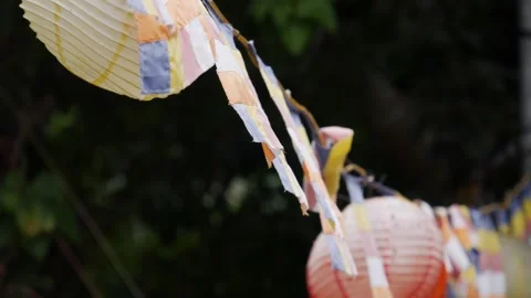 Colorful buddhist prayer flags and hanging paper lanterns waving in the wind aga Stock Footage 343708016