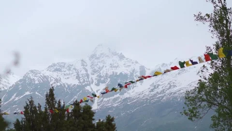 Colorful Buddhist prayer flags fluttering in wind in cloudy day against Snowy mo Stock Footage 273581966