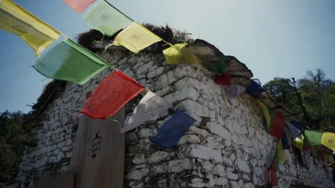 Colorful Buddhist prayer flags fluttering above a whitewashed stone Himalayan Stock Footage 343141283