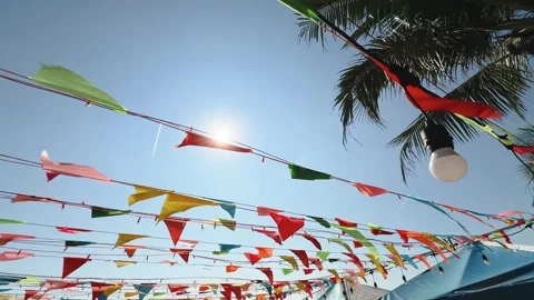 Colorful bunting flags with light bulbs strung and waving across blue sky and Stock Footage 341544307