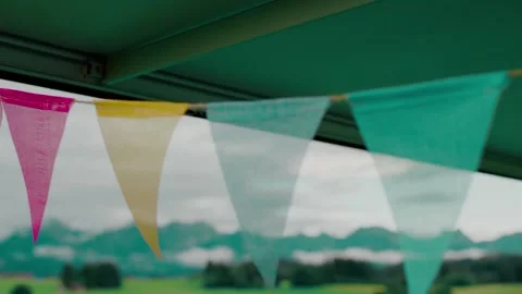 Colorful Bunting Flags Waving under Green Awning, Mountain Panorama, Medium Shot Stock-Footage 341994600