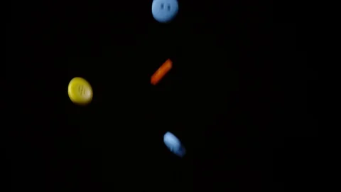 Colorful buttons falling and bouncing on black background, Ultra Slow Motion Stock Footage 86577406