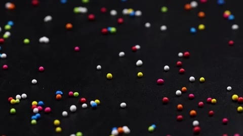 Colorful candy sprinkles falling on black background slow motion, vibrant r.. Stock Footage 332700394