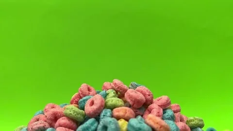 Colorful Cereal Rings Piled in Red Bowl Against Bright Green Background Stock Footage 345274331