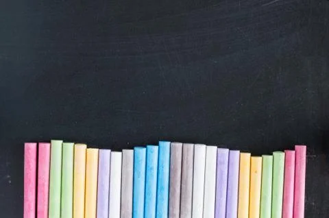 Colorful chalks lined up on blackboard background Stock Photos