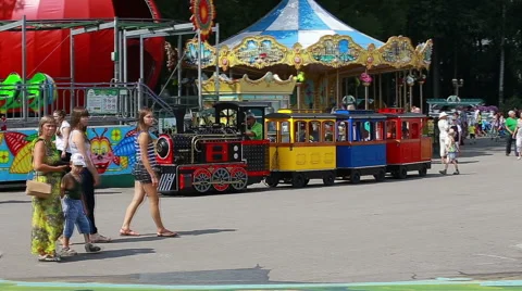 Colorful children's train behaind walking people (Editorial) Stock Footage 65430461