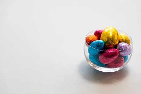 Colorful chocolate easter eggs in a transparent bowl isolated with whit backg Stock Photos