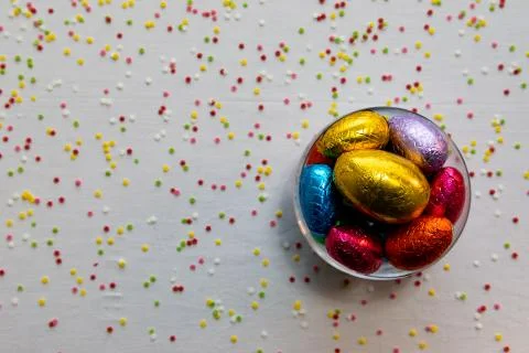 Colorful chocolate easter eggs in a transparent bowl with white background an Stock Photos