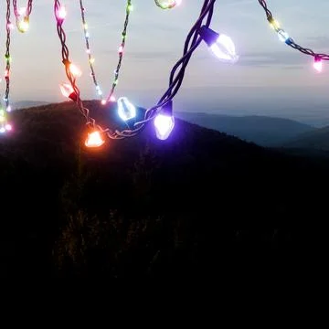 Colorful Christmas Lights Hanging Over a Mountain Landscape at Dusk Stock Photos