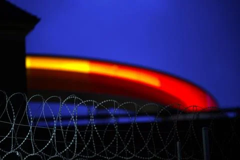 Colorful Circular Structure Behind Barbed Wire at Twilight Stock Photos