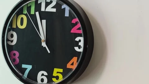 Colorful clock shows time passing on a wall in a modern room 스톡 동영상 342491060