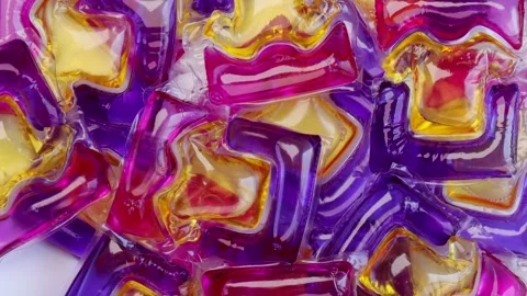 Colorful closeup view of rotating laundry detergent pods with vibrant purple Stock Footage 311237125