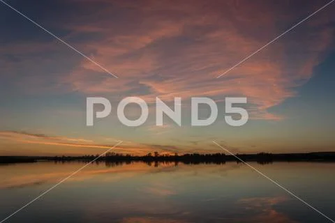 Colorful clouds after sunset reflecting in a lake Stock Photos