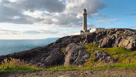 Colorful clouds passing over the lighthouse on the rocky seashore Stock Footage 87810738