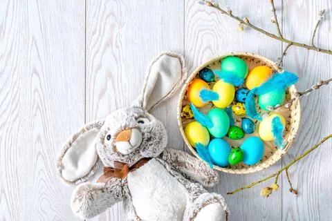 Colorful colored Easter chicken eggs in a wicker basket with feathers, rabb.. Stock Photos