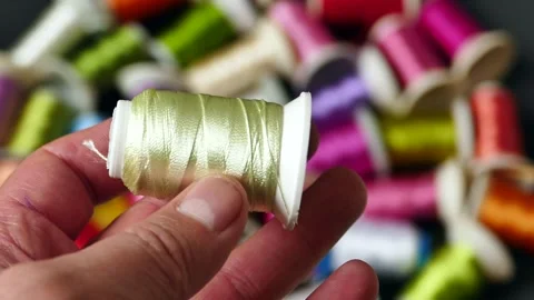 Colorful colored thread wound bobbins, spool of thread in a tailor's hand. 動画素材 172415993