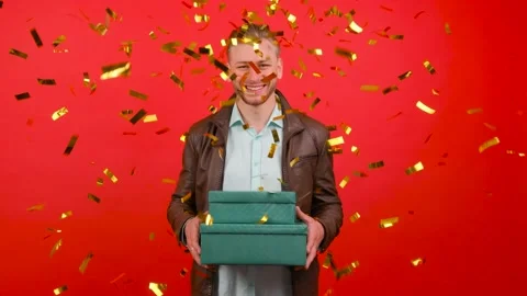 Colorful confetti falling down in front of attractive male with gift box in Stock Footage 142008503