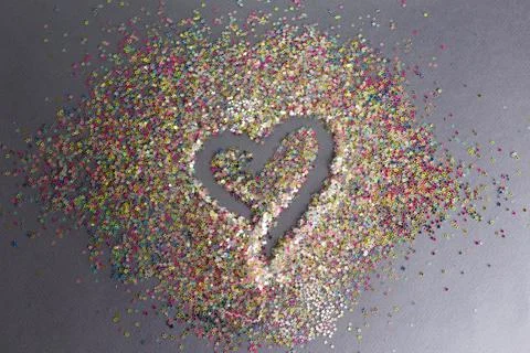 Colorful confetti on a gray background in the shape of a heart. Stock Photos