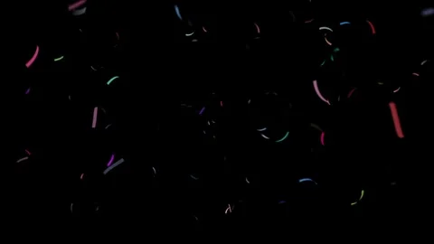 Colorful confetti pieces float gently on black background loop Stock Footage 327594537