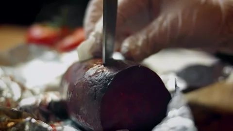 Colorful cook peeling a roasted beet from crinkled foil in portrait, 4K Stock Footage 341111364