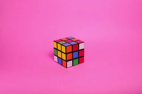 Colorful cube getting touched by a hand in front ot pink background Stock Footage 167738224