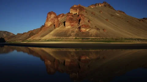 COLORFUL DESERT HILL REFLECTED ON SURFACE OF CALM RIVER Stock Footage 51776184