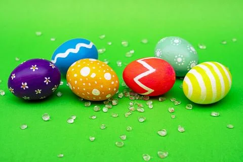 Colorful Designed Easter Eggs Lying on Vibrant Green Background Foto stock
