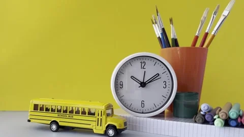 Colorful desk setup featuring a yellow school bus toy, a white clock, a cal.. Stock Footage 309397120
