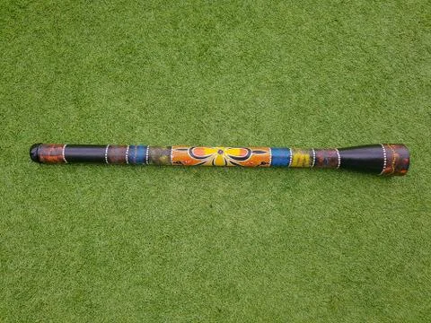 Colorful didgeridoo on a green grass, wind musical instrument. Stock Photos