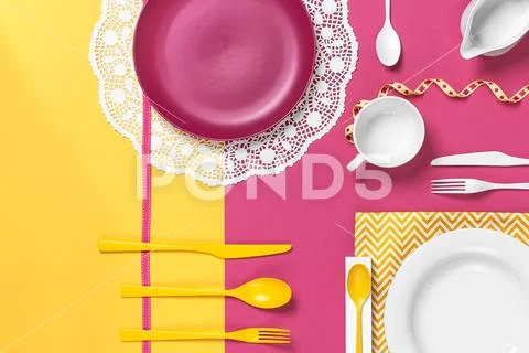 Colorful dishes on a yellow rose table. Stylish arrangement.. Stock Photos