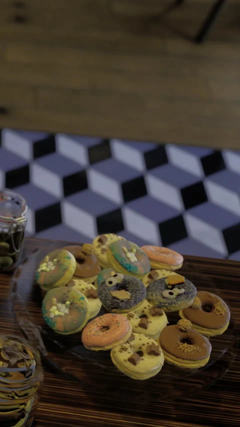Colorful donuts on a wooden board with patterned background at a cafe Stock Footage 331689958