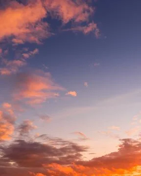 Colorful dramatic clouds lit by a sun against the sunset or sunrise sky. Stock Photos