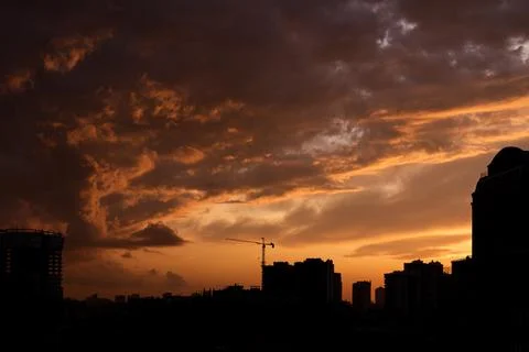 Colorful dramatic sky with clouds at sunset over the urban landscape. Stock Photos