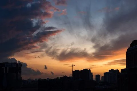 Colorful dramatic sky with clouds at sunset over the urban landscape. Stock Photos