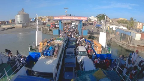 Colorful dressed people enter ferry from Banjul to Barra in Gambia Stock Footage 102779699