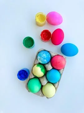 Colorful dyed Easter eggs with open paint pots on white background, depicting Stock Photos