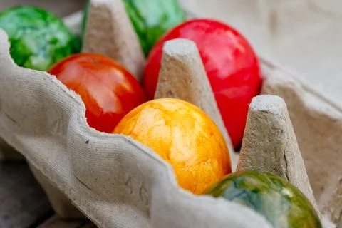 Colorful dyed easter eggs sitting in a cardboard carton Stock Photos