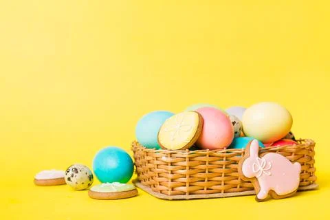 Colorful easter cookies in basket with Multi colors Easter eggs on colored ba Stock Photos