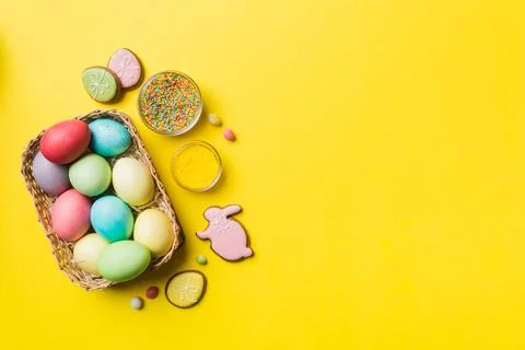 Colorful easter cookies in basket with Multi colors Easter eggs on colored ba Stock Photos