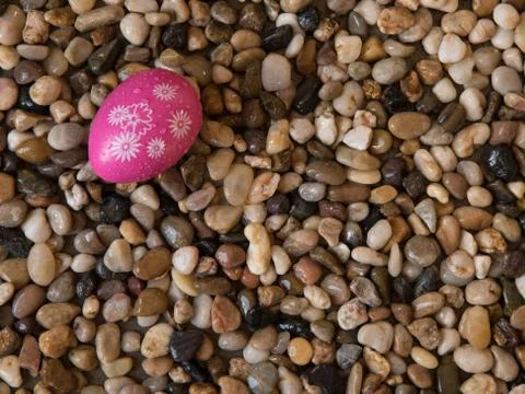 Colorful Easter egg on bed of beach pebbles Stock Photos