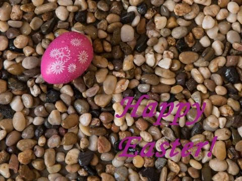 Colorful Easter egg on bed of beach pebbes with Happy Easter greeting Stock Photos