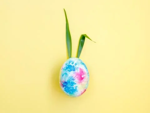 Colorful Easter Egg with Bunny Ears from green grass on yellow Background Stock Photos