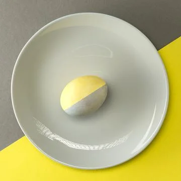 Colorful Easter egg on a gray plate on a yellow-gray background with place fo Stock Photos