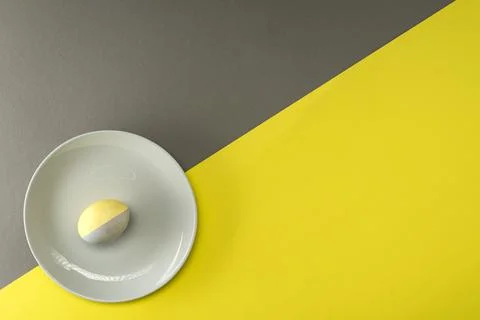 Colorful Easter egg on a gray plate on a yellow-gray background with place fo Stock Photos